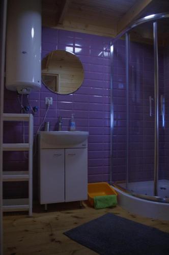 a bathroom with a sink and a shower with purple tiles at Cisowe Domki Nowęcin in Nowecin