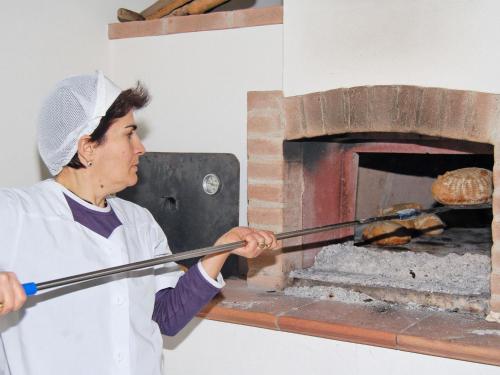 a woman holding a large stick in front of an oven at Su Massaiu in Turri