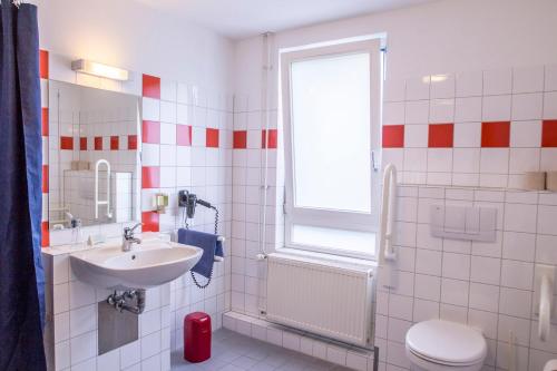 ein Bad mit einem Waschbecken, einem WC und einem Fenster in der Unterkunft Schanzenstern Altona GmbH in Hamburg