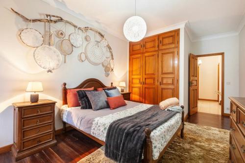 a bedroom with a bed and a dresser with plates on the wall at Vivenda Mar e Terra in Apúlia