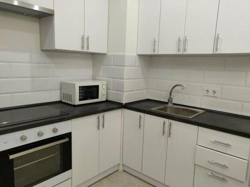 a white kitchen with a microwave and a sink at 1-к кв ж/м Радужный in Odesa