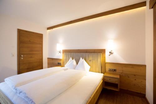 a bedroom with a large bed with white sheets at Appartement Freiblick in Ramsau im Zillertal