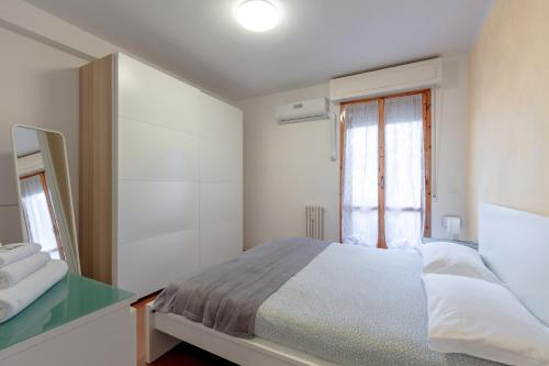 ein weißes Schlafzimmer mit einem Bett und einem Fenster in der Unterkunft Appartamenti Angelica 21 in Pisa