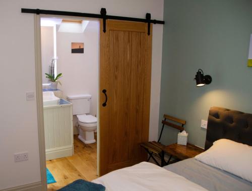 a bedroom with a door leading to a bathroom with a toilet at The Smithy in Ilkley