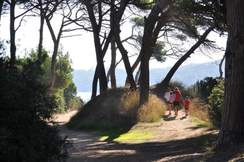 a group of people walking down a dirt road with trees at Hôtel Le Méditerranée in Hyères