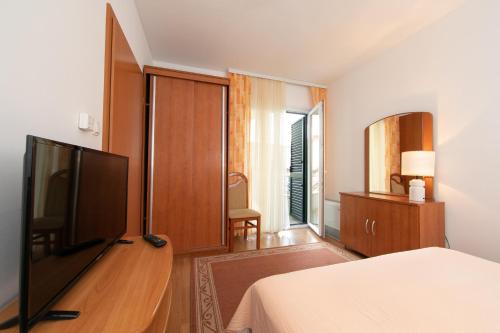 a bedroom with a flat screen tv and a bed at Apartmani Biser in Tučepi