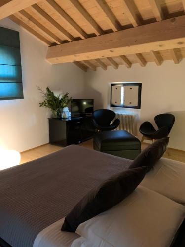 een slaapkamer met een bed en stoelen en een televisie bij Ca'Bert Villa dei Glicini in Castelnuovo del Garda