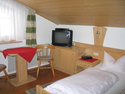 a bedroom with a bed and a tv and a table at Pension Weiß in Hohenwarth