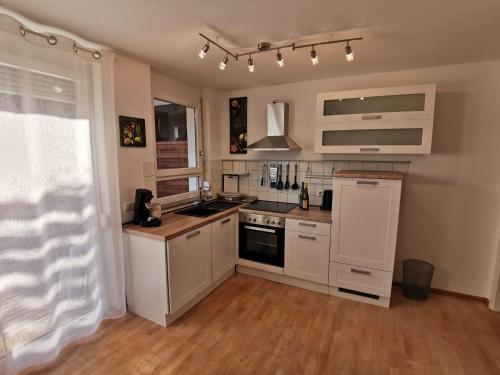 a kitchen with white cabinets and a stove top oven at Ferienwohnung Birkental in Ebringen