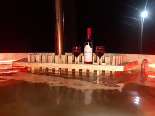 a bottle of wine and two glasses of red wine at Vila Confort in Borşa