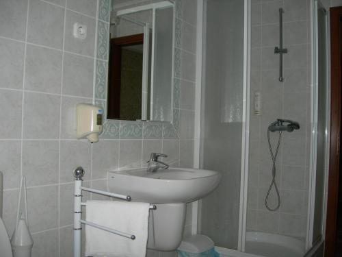 y baño con lavabo y ducha con espejo. en Kígyósi Csárda & Panzió, en Fülöpszállás