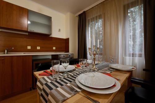 a dining room table with plates and glasses on it at Dolomiti Apartments in Bansko