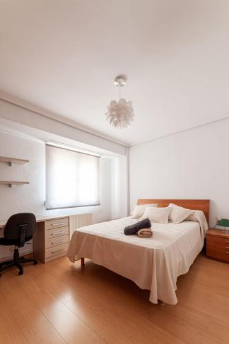 a white bedroom with a bed and a desk at Apartamentos El Llombo in Ontinyent