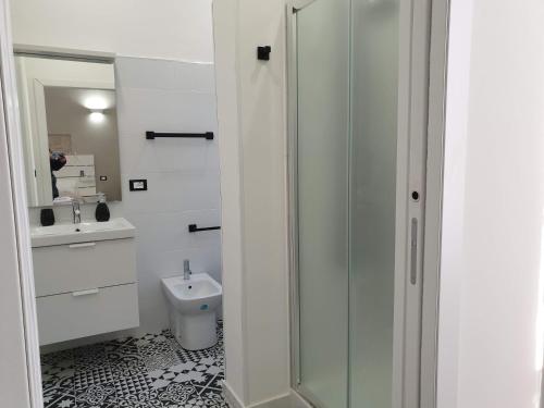 a white bathroom with a toilet and a sink at Duomo Rooms b&b in Lentini