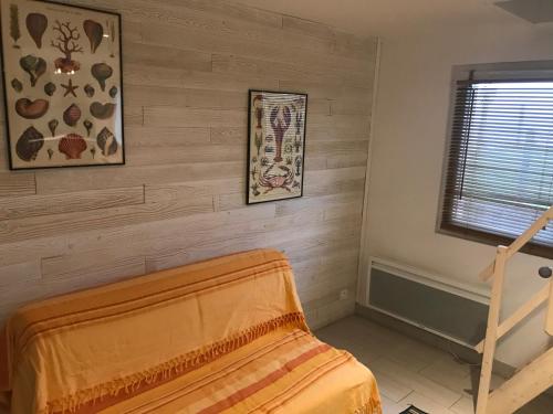 een slaapkamer met een houten muur en een bed bij Accès direct mer. Plage du Débarquement in Ouistreham