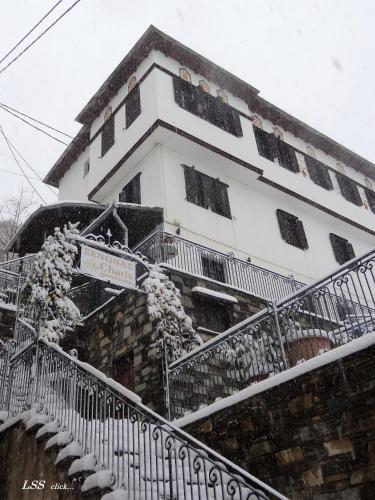 a building with snow on the steps of it at Charis Guesthouse in Makrinítsa