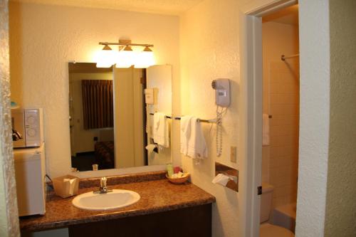 uma casa de banho com um lavatório e um espelho grande em The Sturgis Motel em Sturgis