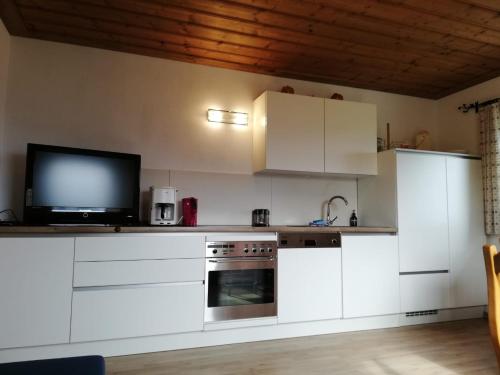 uma cozinha com armários brancos e uma televisão de ecrã plano em Aignerbauer Mittersill em Mittersill