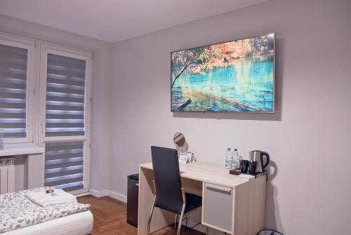 Habitación con escritorio, cama y una pintura en la pared. en Dr Mandryk HOUSE, en Lublin