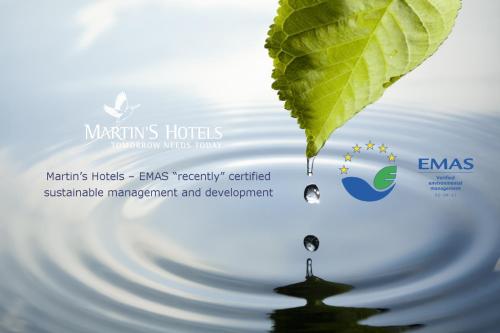 a green leaf hanging over water with a water drop at Martin's Manoir in Genval
