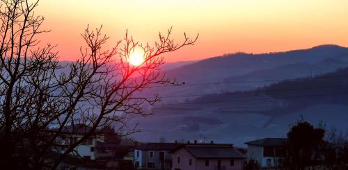 a sunset with the sun setting over a mountain at Agriturismo Mondo in Bubbio