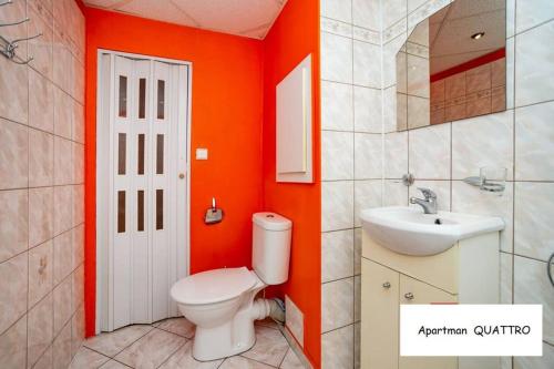 La salle de bains orange est pourvue de toilettes et d'un lavabo. dans l'établissement Apartman QUATTRO, à Sokolov
