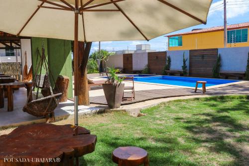 um pátio com uma mesa, um guarda-sol e uma piscina em Pousada Ubajara em Ubajara