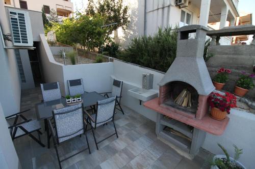 d'une terrasse avec une cheminée, une table et des chaises. dans l'établissement Apartments Klaudija, à Čižići