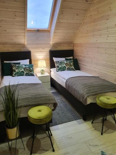 two beds in a room with wooden walls at Ekosfera Piława Apartamenty z podgrzewanym basenem in Borne Sulinowo