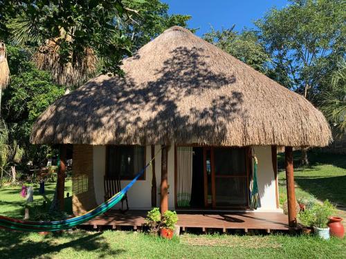 a small hut with a thatch roof and a hammock at Pucté 13 in Bacalar