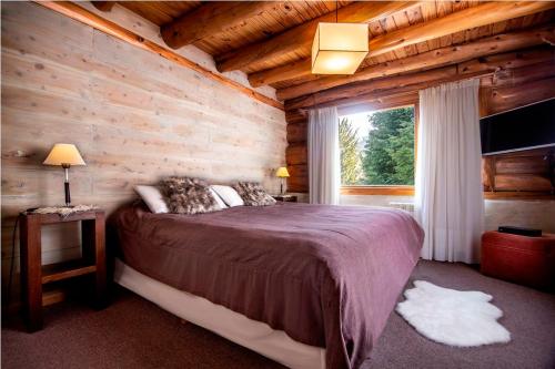um quarto com uma cama grande num chalé de madeira em Hosteria Sudbruck em San Carlos de Bariloche