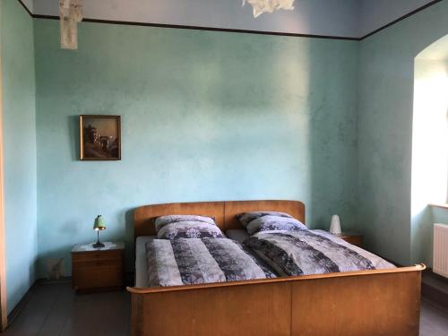 Ce lit se trouve dans une chambre dotée d'un mur bleu. dans l'établissement Wolke 33, à Annaberg-Buchholz