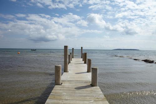 a wooden dock in the water on a beach at Camp Hverringe in Dalby