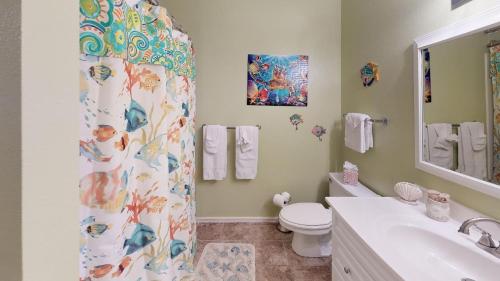 La salle de bains est pourvue d'un rideau de douche, de toilettes et d'un lavabo. dans l'établissement Coastal Cottage townhouse, à South Padre Island