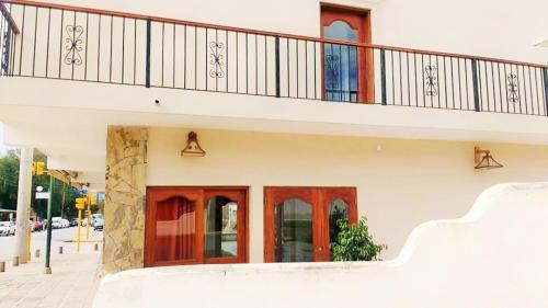 a white building with red doors and a balcony at Portal De Los Valles in Chicoana
