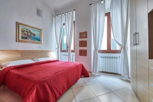 a red bed in a white room with windows at Florence&Us Santa Croce in Florence