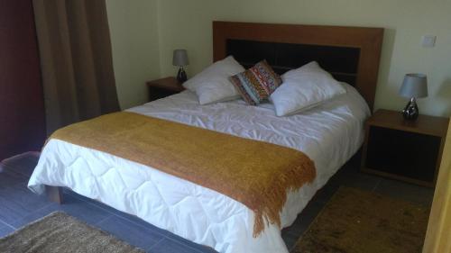 a bedroom with a bed with white sheets and pillows at Matilde House in São Vicente