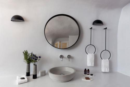 a white bathroom with a sink and a mirror at The Vasilicos in Imerovigli