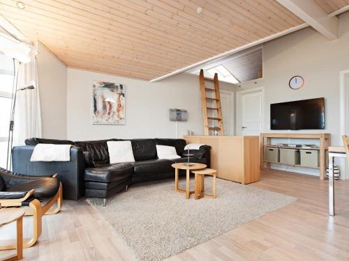 a living room with a black leather couch and a tv at 7 person holiday home in R dby in Rødby