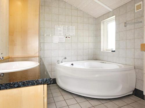 ein Badezimmer mit einer großen weißen Badewanne und einem Waschbecken in der Unterkunft Three-Bedroom Holiday home in Knebel 21 in Hadsund