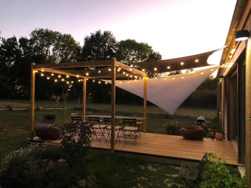 a pergola with lights and a picnic table on a deck at Rejaillir in Saint-Ours