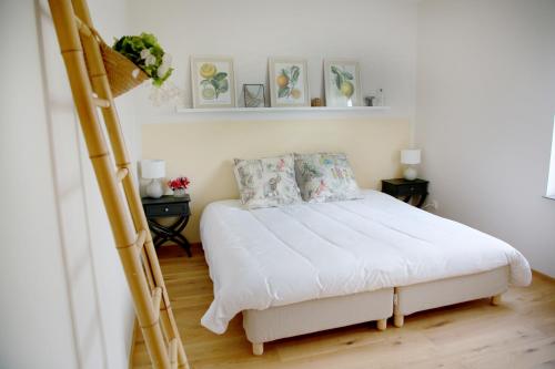 een slaapkamer met een bed met witte lakens en kussens bij Rejaillir in Saint-Ours