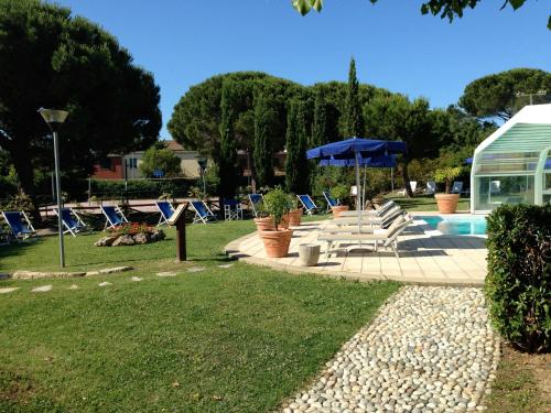a pool with chairs and umbrellas in a yard at Hotel La Buca Del Gatto in Marina di Cecina