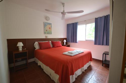 Un dormitorio con una cama con sábanas rojas y una ventana en Posada del Lago en Villa Carlos Paz