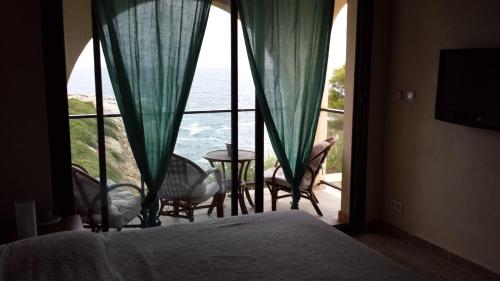 a bedroom with a large window with a view of the ocean at Castelia in Lumio