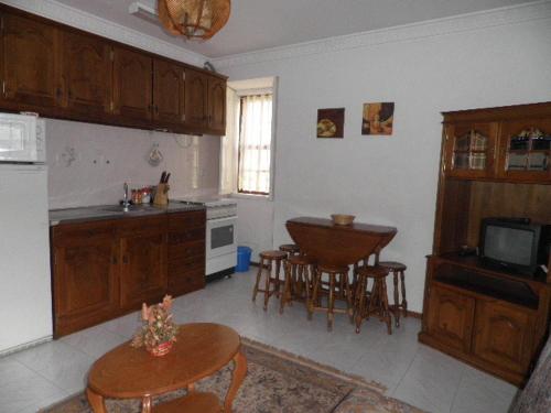 una cocina con armarios de madera, mesa y sillas en Casa Das Lages, en Alvoco da Serra