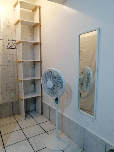 a bathroom with a fan and a mirror at Hostal Maple in Querétaro