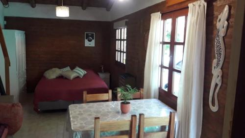 Un dormitorio con una cama roja y una mesa con una mesa. en Casa Sur, en El Bolsón