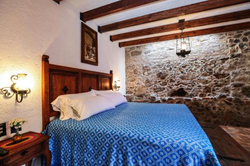 1 dormitorio con cama y pared de piedra en El mesón del Quijote, en San Miguel de Allende