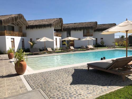 a resort with a swimming pool with chairs and umbrellas at PARADISE EN VICHAYITO II in Vichayito